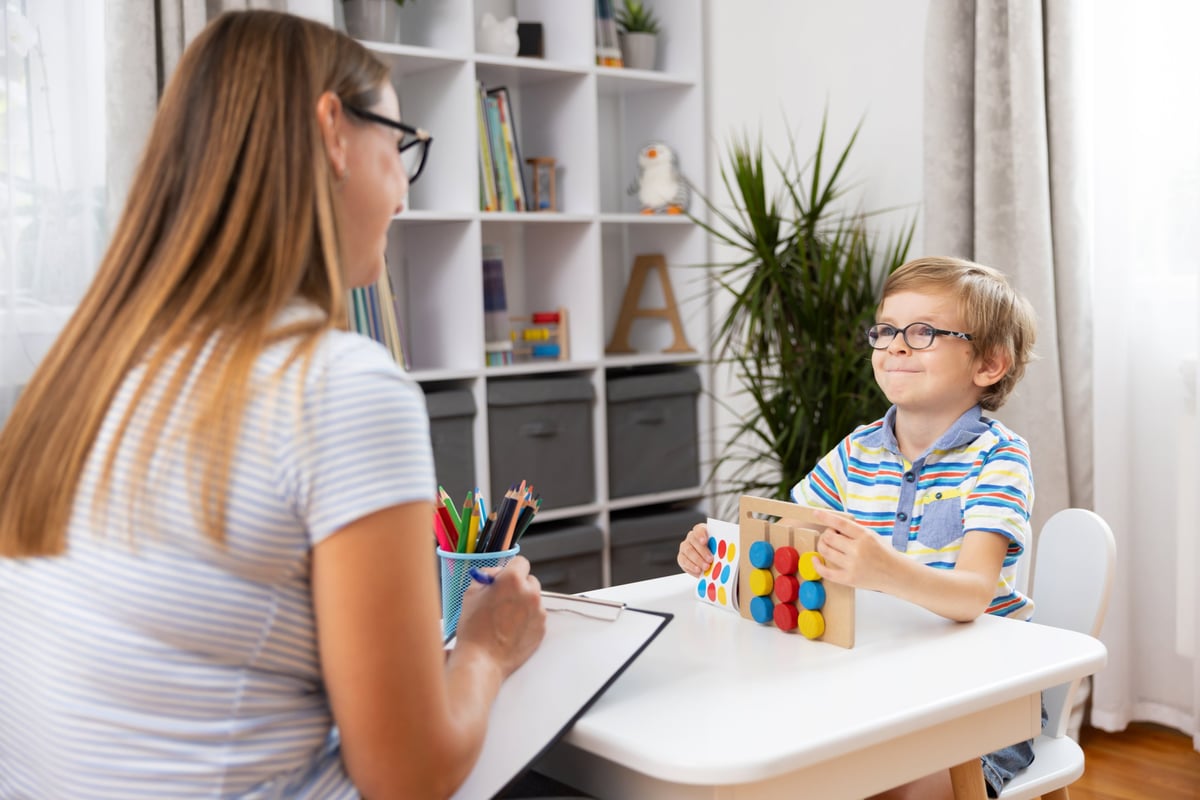 A child playing with a colourful educational toy alongside an adult in a bright learning space